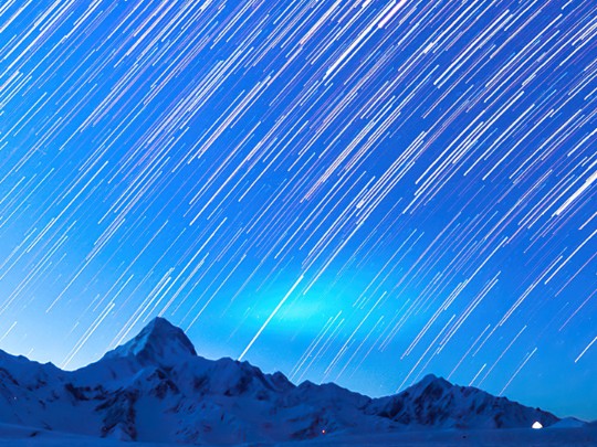 Danza celestial: capturando senderos de estrellas por encima de las montañas cubiertas de nieve